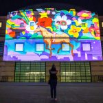 Digital artwork projection featuring brightly coloured background of flowers with girl riding a horse.