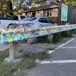 Painting of frog, birds and flowers on parking lot guardrail.