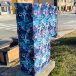 Colourful patterened vinyl wrapped utility box next to a street.
