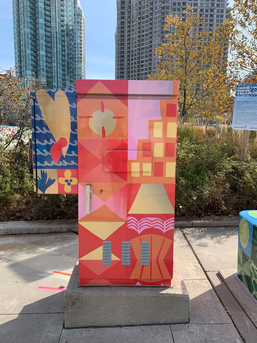 Utility box on a sidewalk painted with red, orange, pink, yellow and blue shapes.