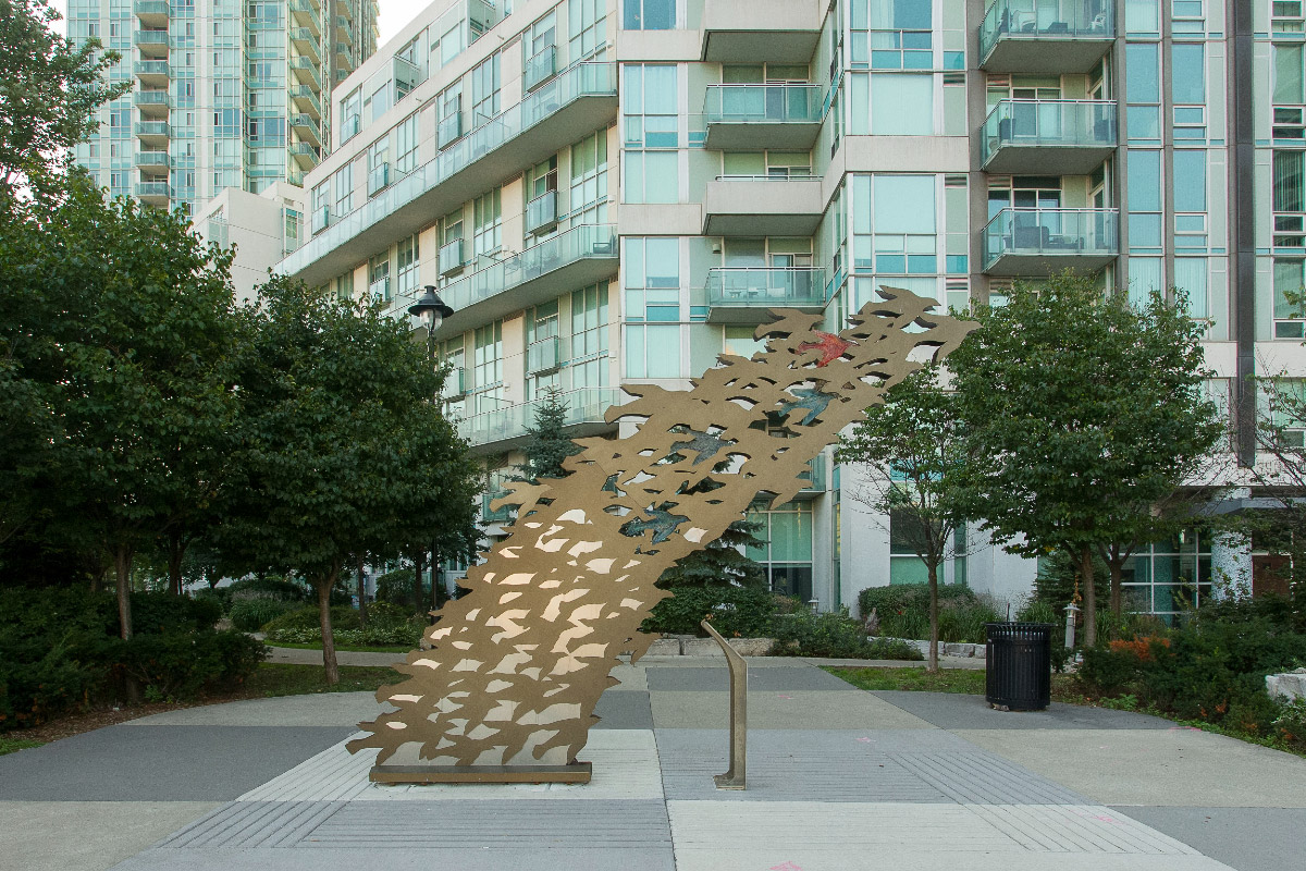 Metal sculpture of a flock of birds flying together.