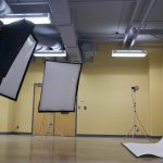 2 lighting softboxes in front of a white backdrop in an empty photography studio.