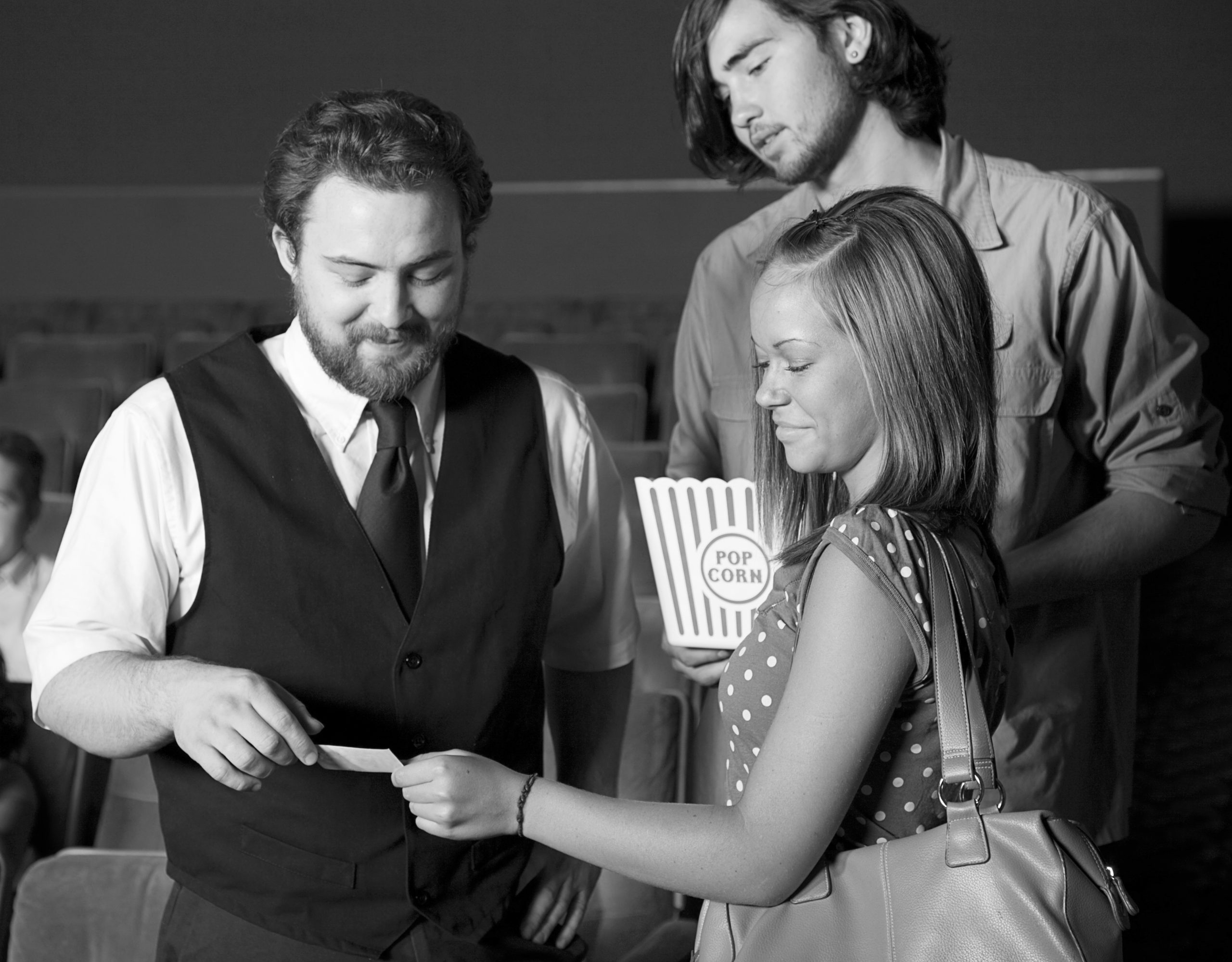 A young couple with an usher in a movie theater.