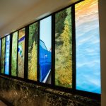 Ten panels with printed images of landscapes on them inside a hallway