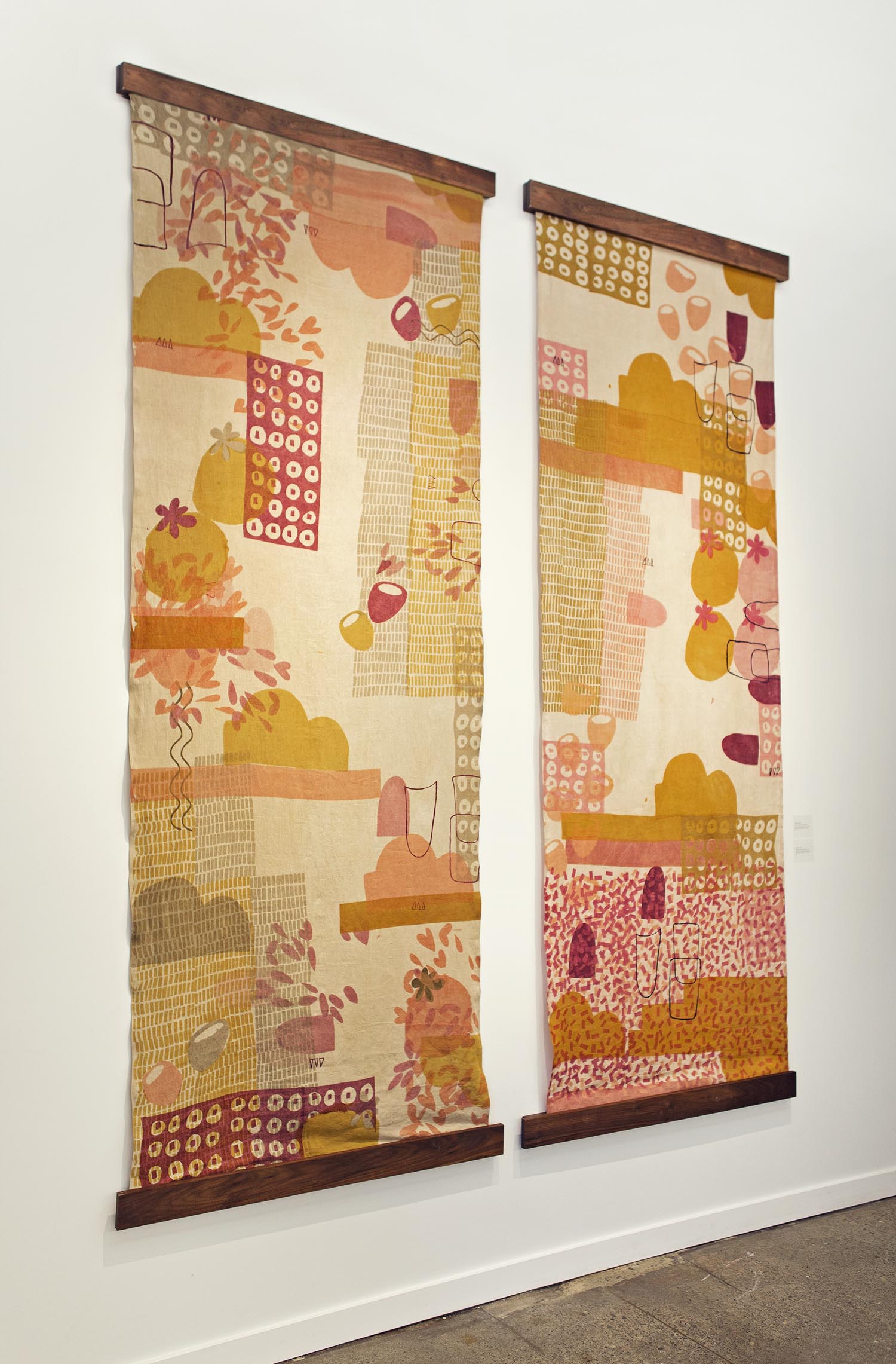 Two long tapestries with pink and orange patterns hanging on a wal