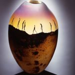 A glass vase with a painted scenery of people walking through a desert.
