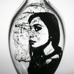 A clear vase with black paint depicting tree branches and a woman's side profile.