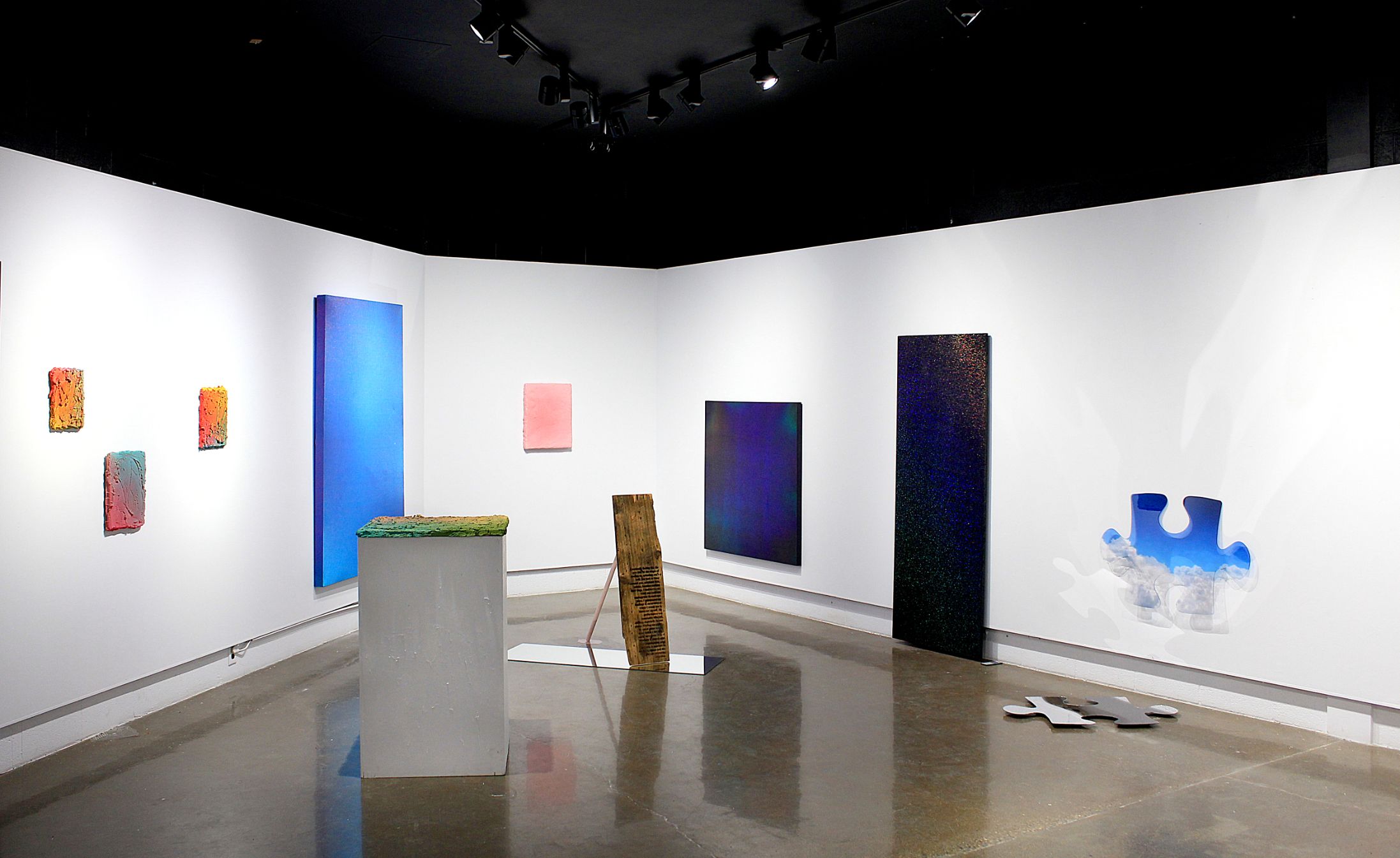 A gallery installation featuring multiple paintings.