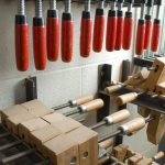 A large collection of metal and wooden clamps arranged on wall hooks.