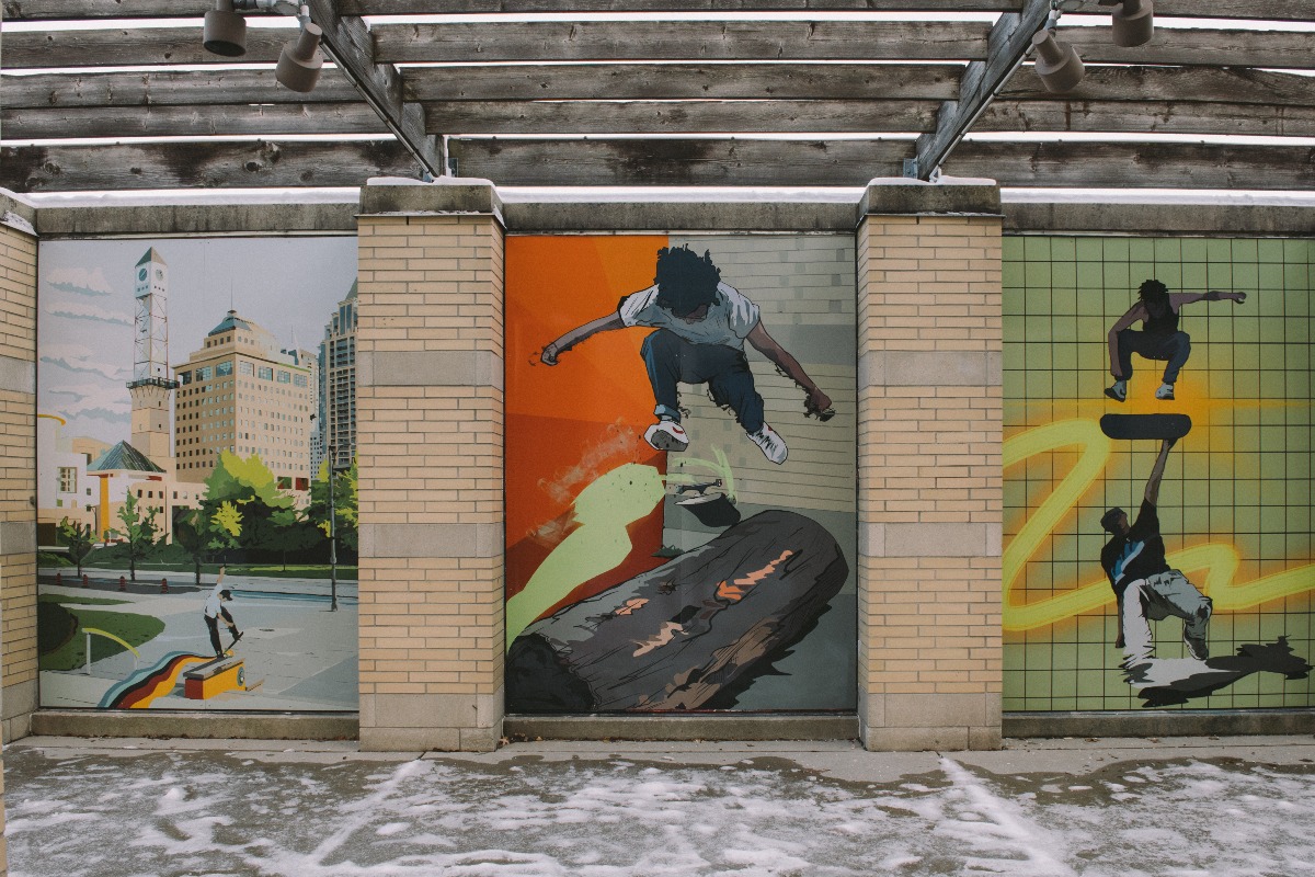 Brightly coloured mural panels showing areas of the city and the skatepark with people skateboarding and break dancing.