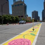 A ground mural painted along a bicycle lane that depicts a vine of pink flowers.