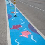A ground mural painted along a bicycle lane that depicts fish underwater.