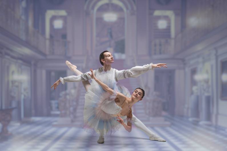 two ballerinas posing in front of an elegant backdrop