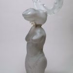 White glass sculpture of a moose with a female body.