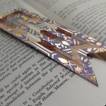 A wooden bookmark with designs all over it.