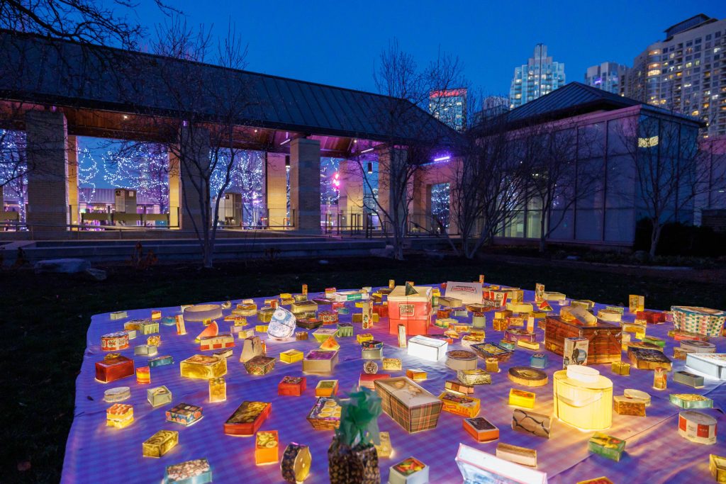 An outdoor art installation, The Guest's Shadow, that resembles a picnic blanket with food items scattered on top.