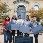 A group of Black students holding historic plaques that honour Black Canadian history.