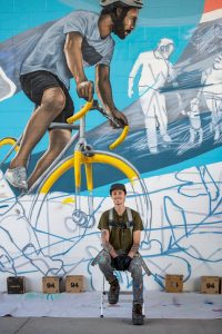 Artist sitting in front of mural artwork in progress