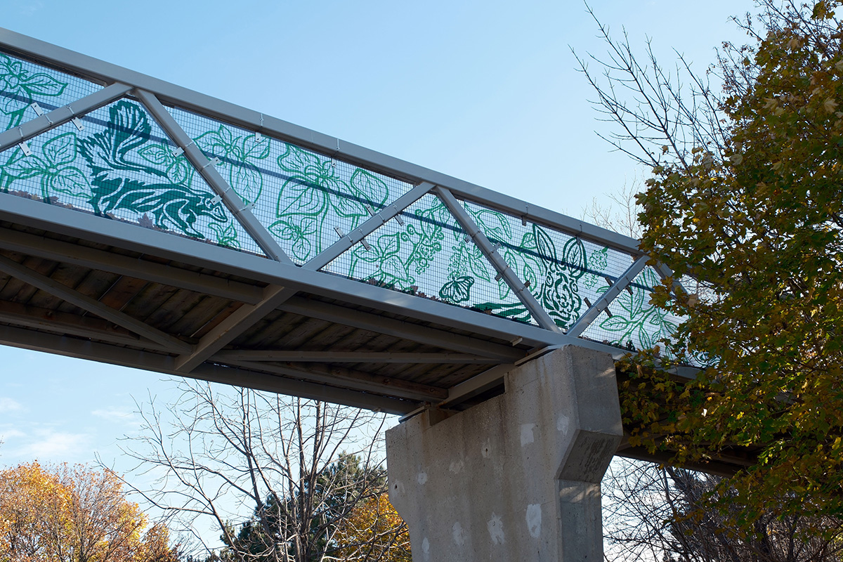 A pedestrian bridge with public artwork displayed on it.