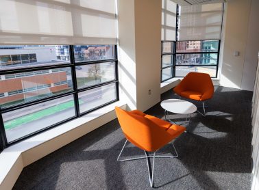 A quiet conversation zone at the library featuring an orange chair paired with a white table.