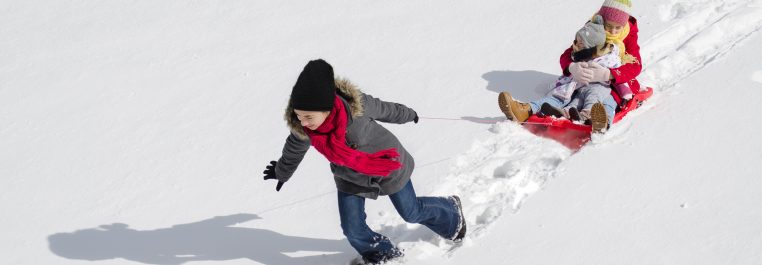 child pulling siblings on a sled