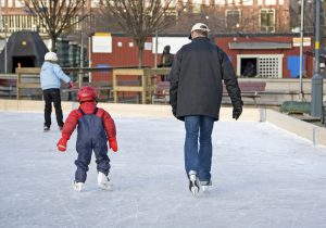 child and man skating on an outdoor skating rink