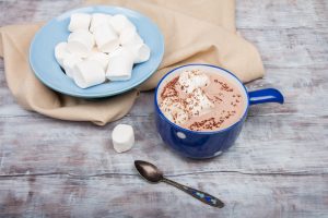 Blue cup of hot chocolate and marshmallows on wooden background. Winter Christmas drink