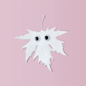 White Halloween leaf with funny eyes on pink background. 