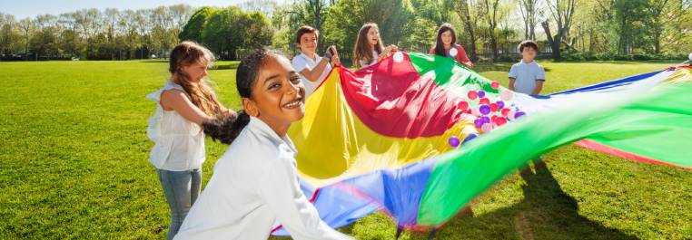 children playing outside with a colourful parachute