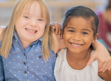 Two young girls smiling and hugging