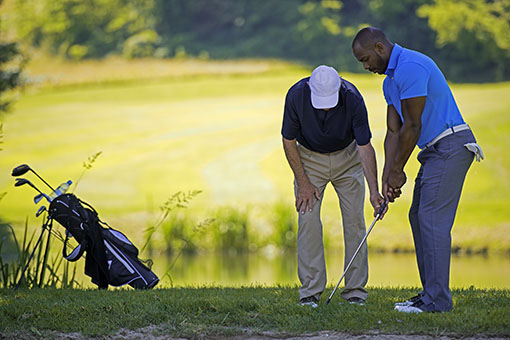 Golf pro teaching a golfer on the driving range.