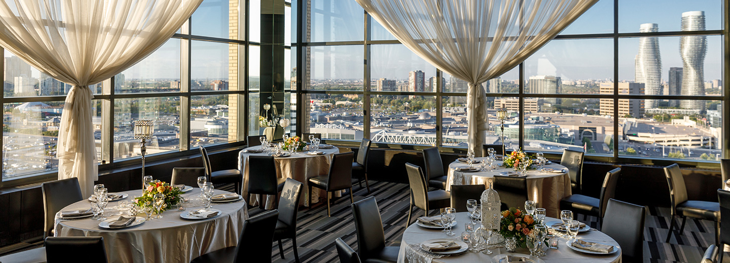 Round tables with gold tablecloth and black chairs overlooking the Mississauga skyline