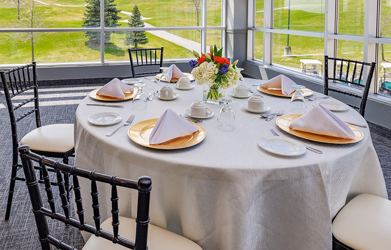 Brown and beige tables with natural centrepieces overlooking the fairway at BraeBen Golf Course